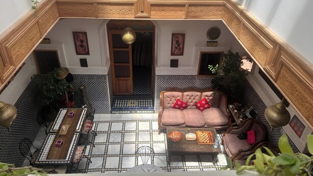 A traditional Moroccan interior with a patterned floor, a sofa with cushions, a coffee table, and a hanging lamp. - Riad Tafoukt Palace (Fes)