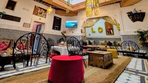 A spacious dining area with high ceilings, hanging plants, and traditional decor. - Riad Tafoukt Palace (Fes)