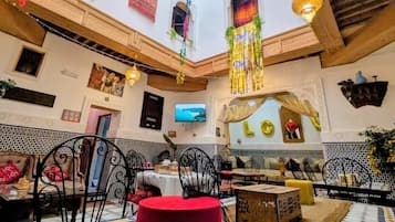 Un comedor amplio con techos altos, plantas colgantes y decoración tradicional.