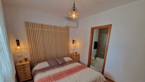 Un dormitorio con cama, cabecera de madera, mesitas de noche y un espejo.