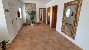 Un pasillo con pared de piedra, una planta en maceta y un espejo grande a la derecha.