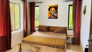 Un dormitorio con cama, un cuadro en la pared y una ventana con cortinas.