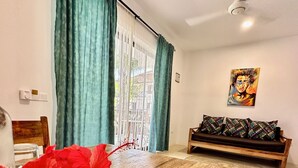 Un comedor con una mesa de madera, un jarrón con flores rojas y un sofá con cojines estampados.