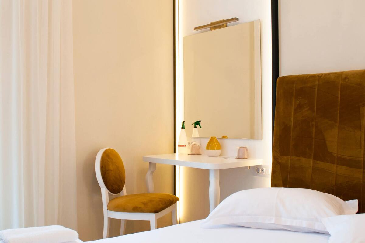 A hotel room with a bed, a chair, a desk, and a mirror.