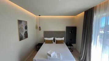Una habitación de hotel moderna con una cama grande, un cabecero de diseño circular, una obra de arte en la pared, una mesita de noche y una ventana con cortinas.
