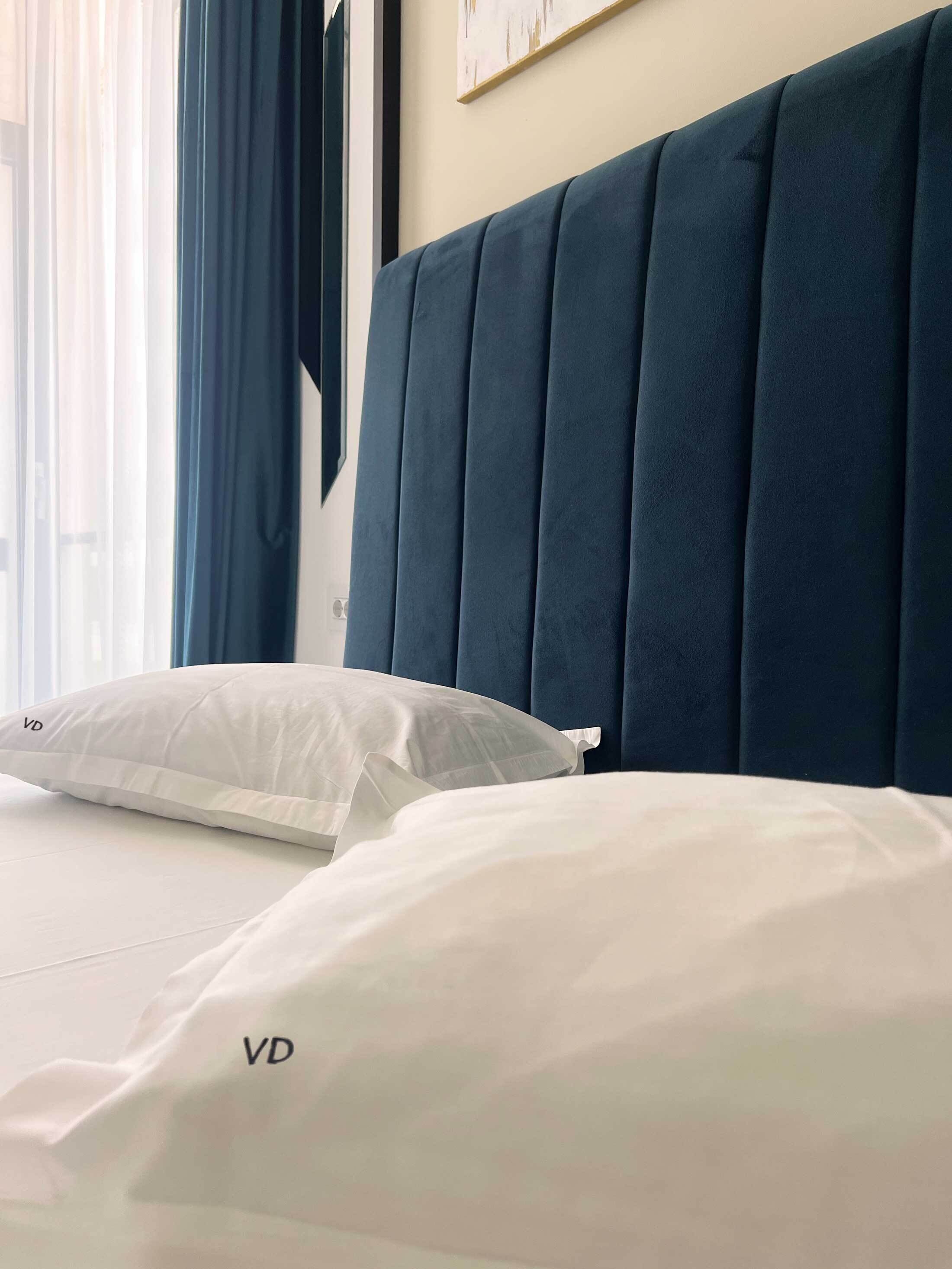 A bed with white bedding and a dark blue headboard in a hotel room.