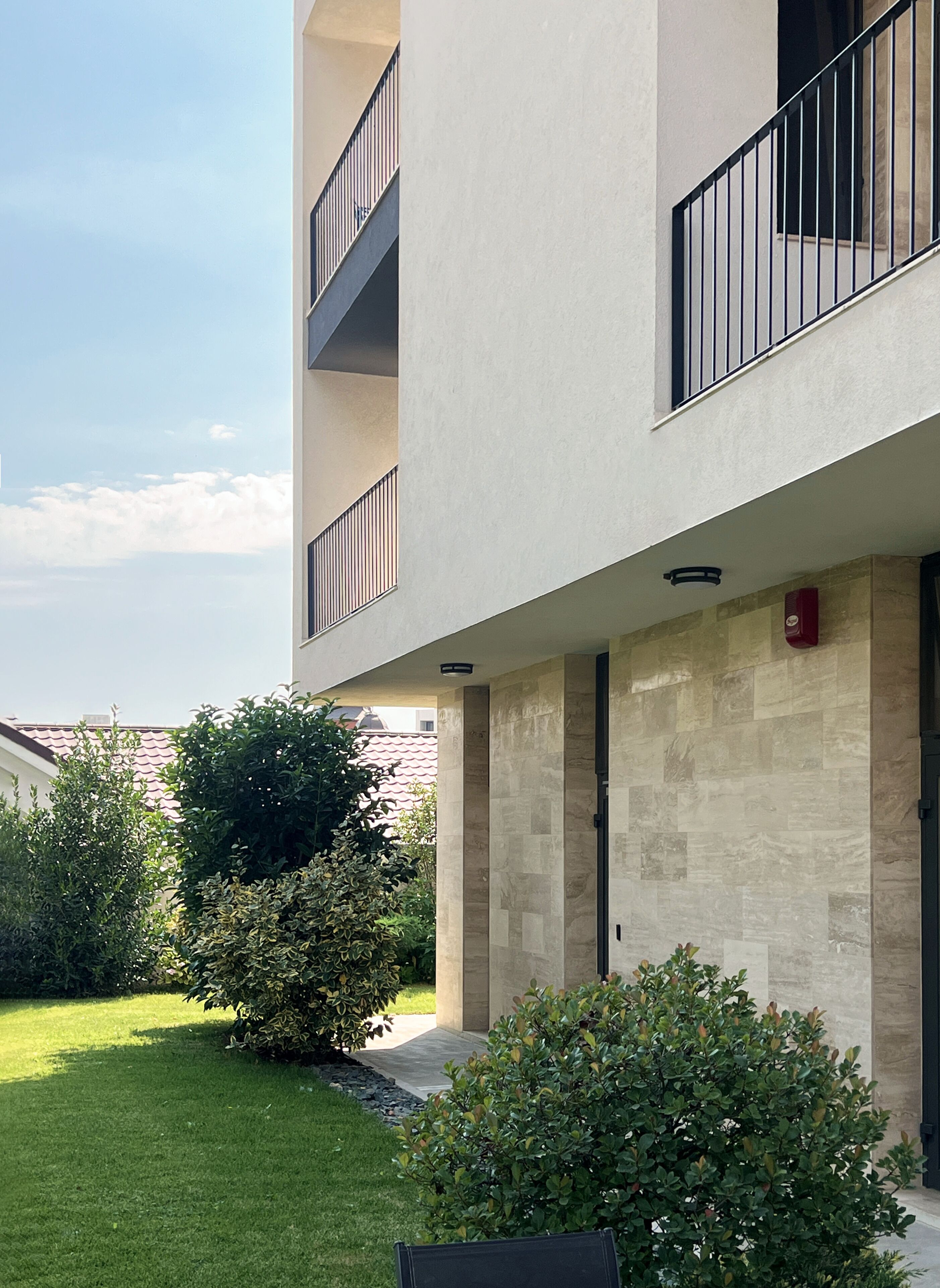 Un bâtiment moderne à la façade plate, doté de nombreux balcons et d’une pelouse bien entretenue.