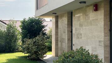 Un bâtiment moderne à la façade plate, doté de nombreux balcons et d’une pelouse bien entretenue.