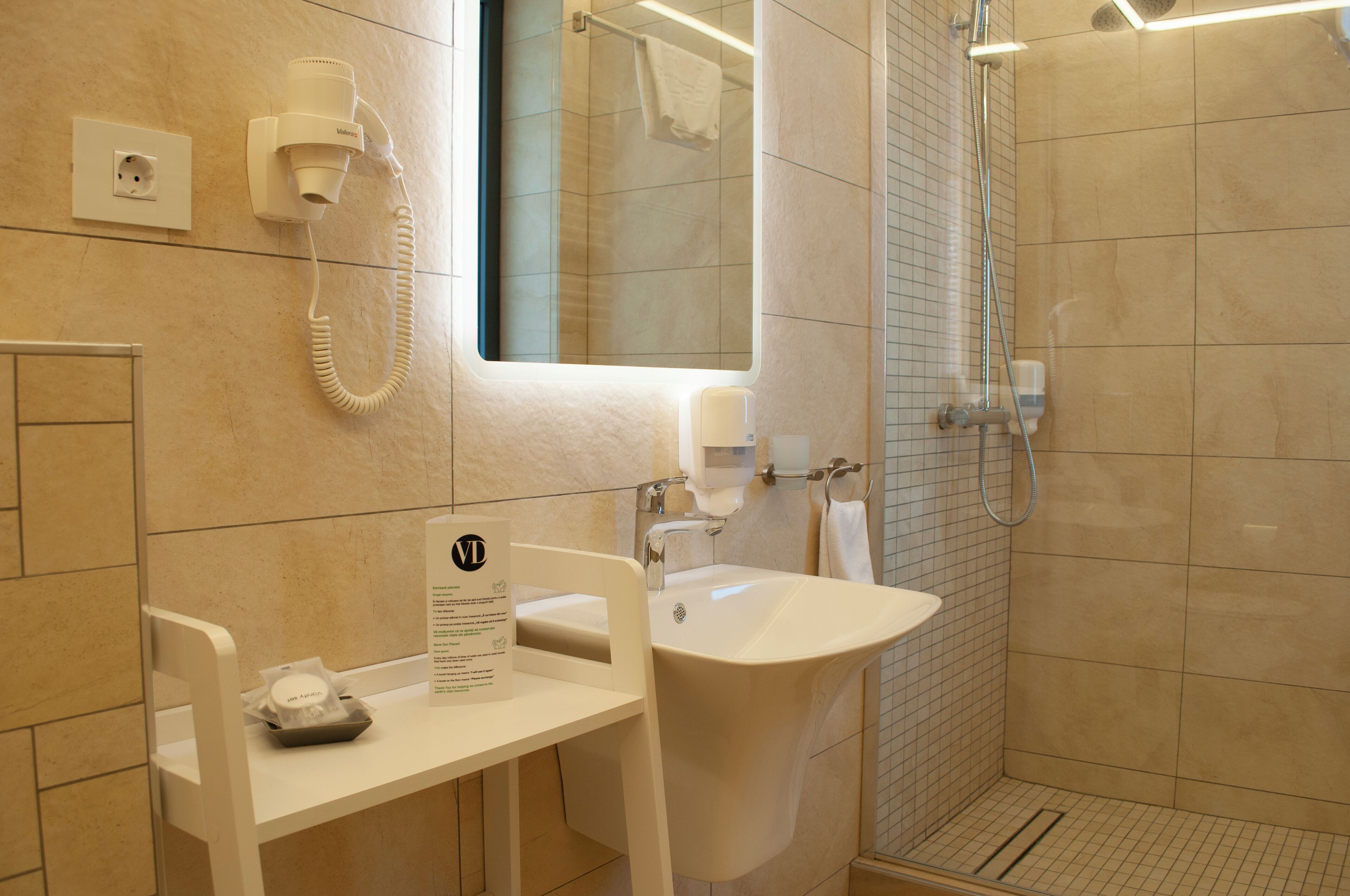 A bathroom with a sink, mirror, towel rack, and a shower area.