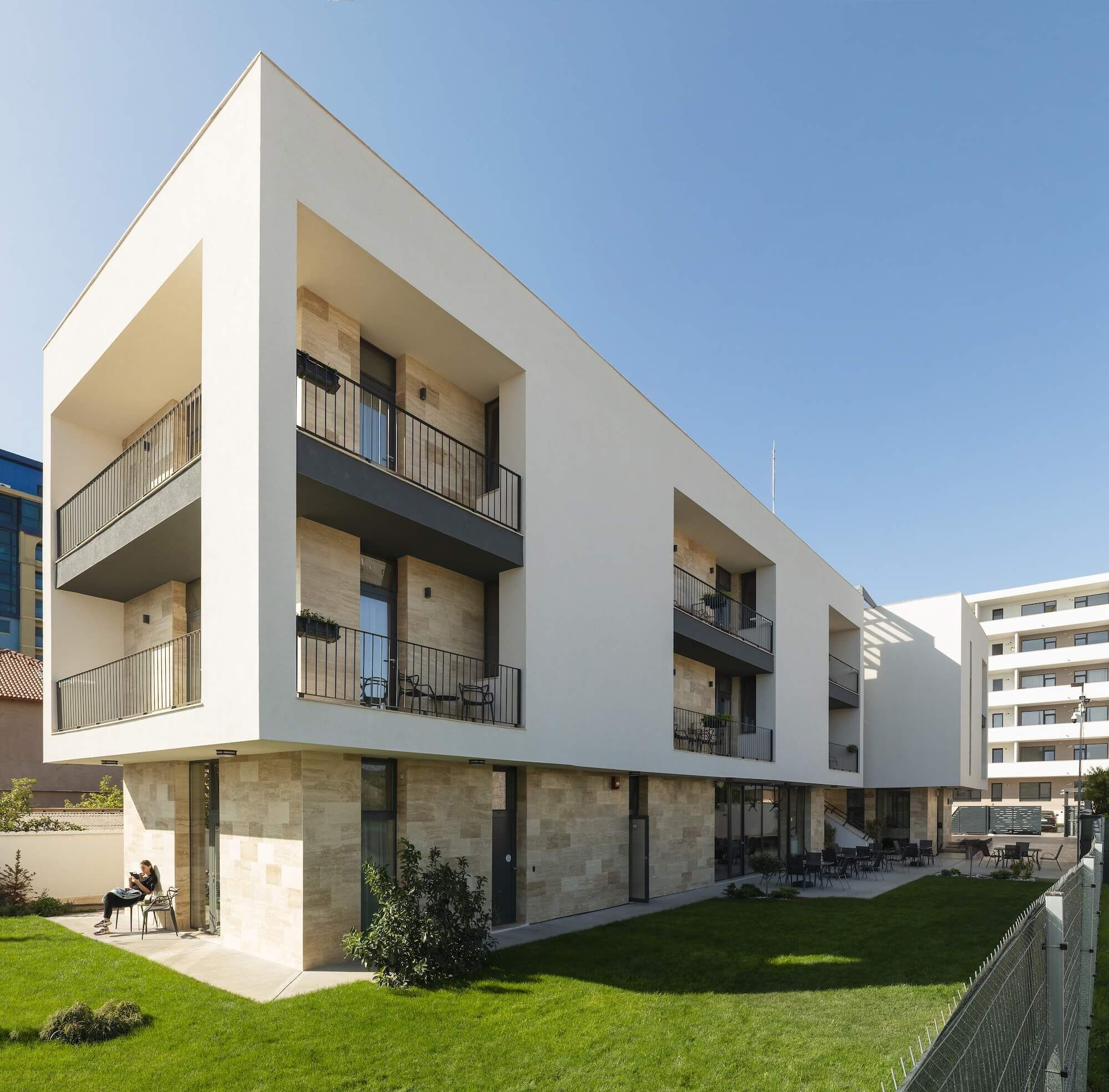 Un immeuble moderne à plusieurs étages, doté de balcons, d’un toit plat et d’une pelouse bien entretenue.