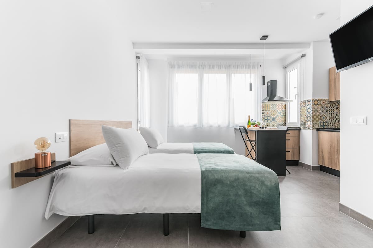 Una habitación de hotel moderna con una cama, una mesita de noche y un escritorio con una silla.