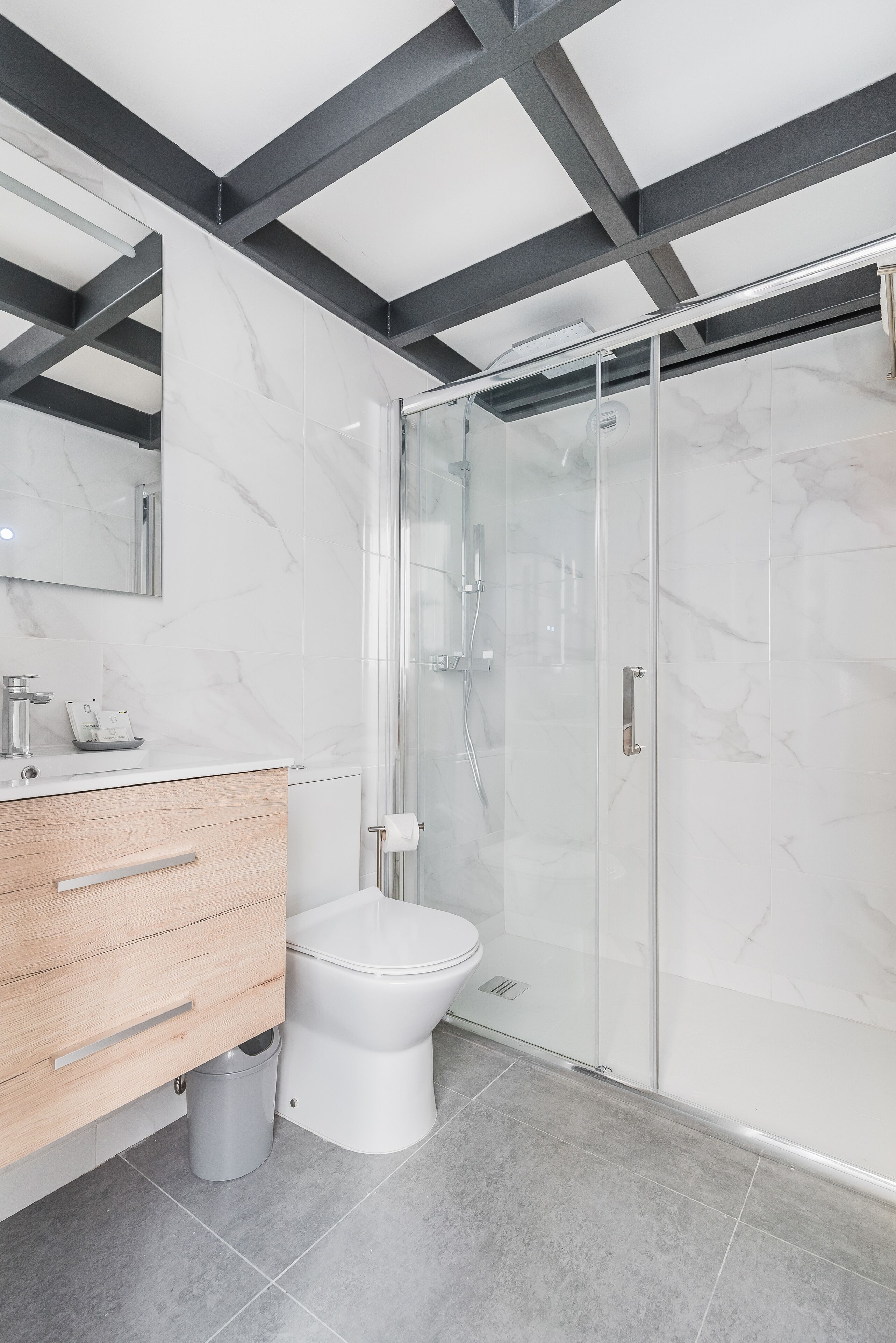 Un baño moderno con tocador de mármol, inodoro y ducha con cerramiento de vidrio.