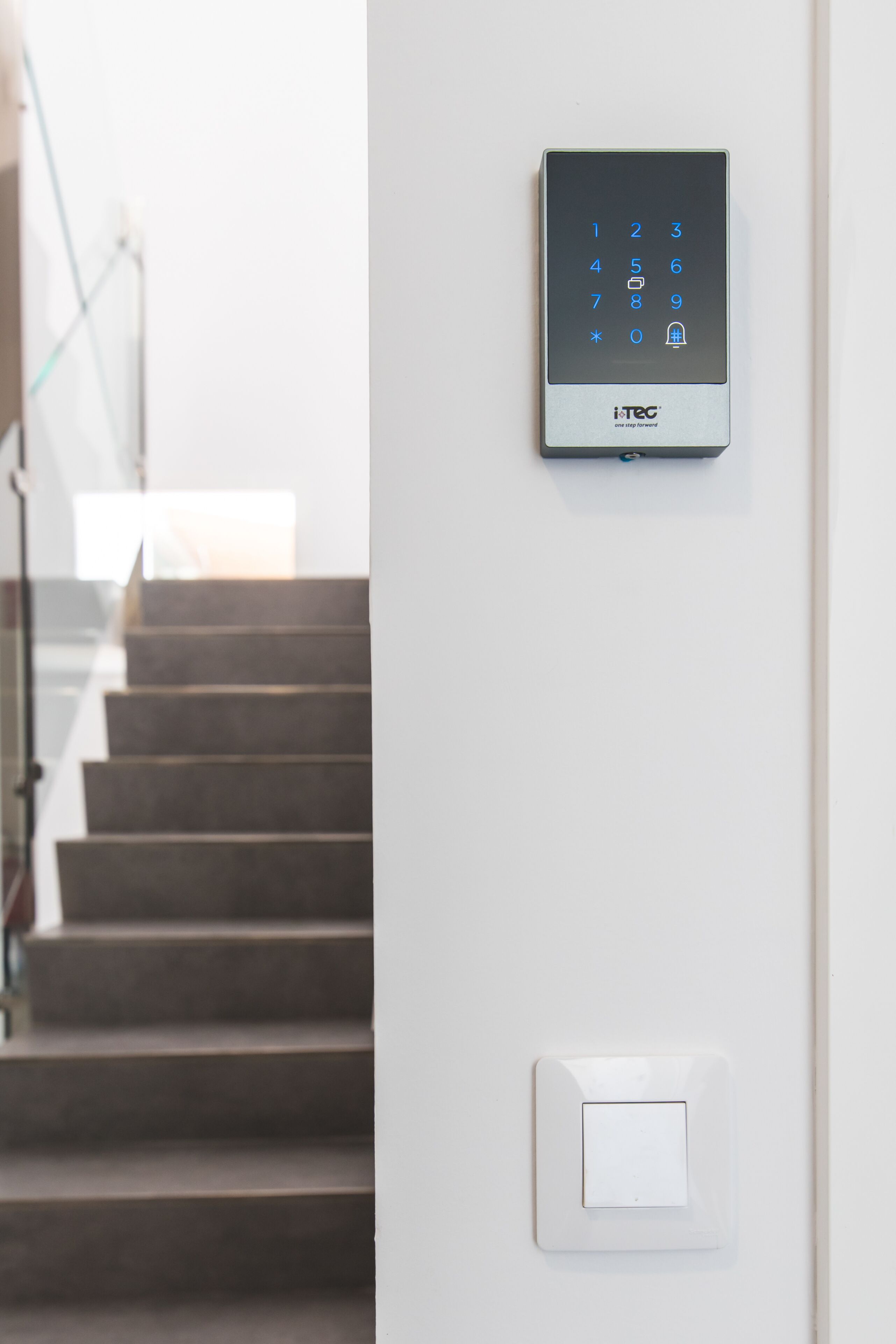 A wall-mounted intercom system with a keypad and a light switch.