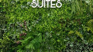 Una pared con el texto "OpenSea SUITES" en medio de una exuberante vegetación.