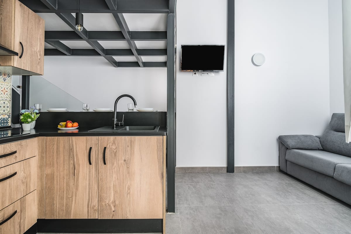 Una cocina moderna con armarios de madera, encimera negra y pileta integrada.