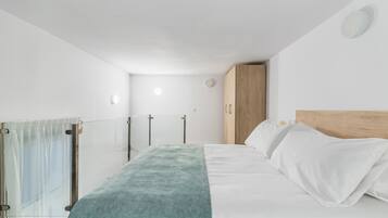 Un dormitorio moderno con una cama, un armario de madera y un ventanal de vidrio que da a un balcón.