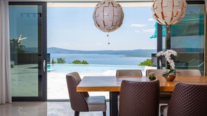 Un comedor con vistas al mar, una mesa de madera y sillas de cuero.