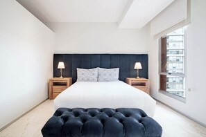 A modern bedroom with a large bed, two bedside tables, and a window with a view of buildings. - 1BR in Nuevo Polanco · Pool, Gym & Padel (Ciudad de México)