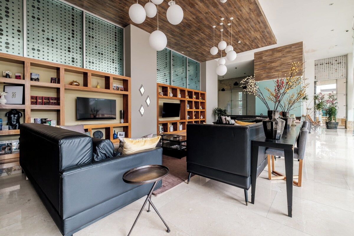 A modern living room with a sofa, armchair, TV, and shelves.