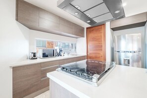 A modern kitchen with a built-in stove, a microwave, and a refrigerator.