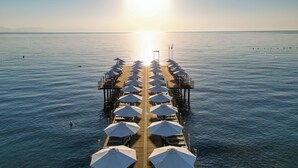 Un muelle con hileras de sombrillas que se adentran en aguas tranquilas, bajo un cielo despejado.