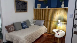 Ein Schlafzimmer mit Bett, Kissen, einem Nachttisch mit Lampe, einer Weltkarte an der Wand und einer blauen Akzentwand.