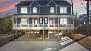 Una casa a due piani con un balcone al piano terra, un pontile in legno e una scala che conduce al piano superiore.