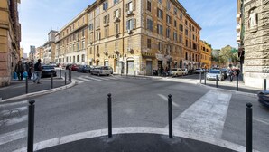Straßenansicht mit Gebäuden, Autos und Fußgängern.