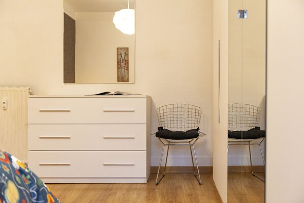 A bedroom with a white dresser, a chair, and a mirror on the wall. - Rome La Sapienza Apartment (Rome)