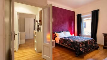 Quarto com cama, guarda-roupa, radiador e janela com cortinas.