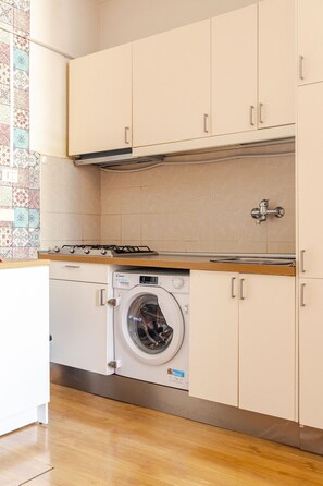 A compact kitchen with a built-in washing machine, wooden countertop, and tiled backsplash. - Rome La Sapienza Apartment (Rome)