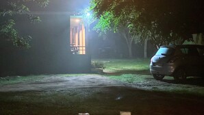Une allée faiblement éclairée mène à une maison dont on aperçoit la porte de garage.
