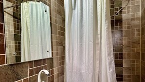 Une salle de bain avec un lavabo blanc, un miroir et un rideau de douche.