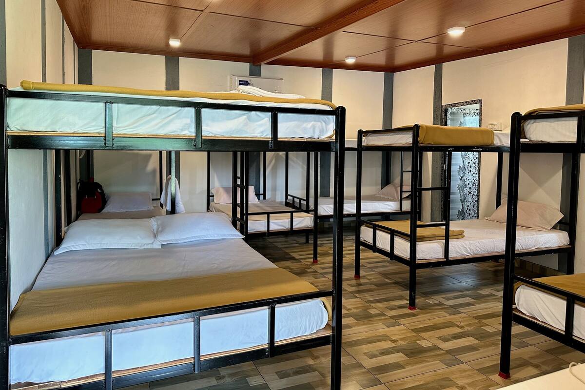 Een kamer met stapelbedden, houten vloeren en een plafond met inbouwspots.
