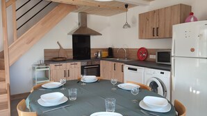 Een moderne keuken met houten kastjes, een eettafel gedekt voor vier personen en een inbouw wasmachine.