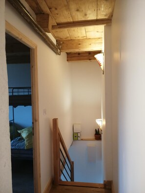 Una stretta scala con ringhiere in legno che conduce a una camera da letto con letti a castello.