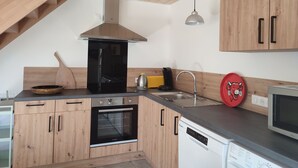 Een moderne keuken met houten kastjes, een zwarte oven, een vaatwasser en een magnetron.