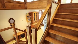 A wooden staircase with a handrail and a view of a kitchen area with cabinets and a countertop. - Brambleberry Barn (Spilsby)