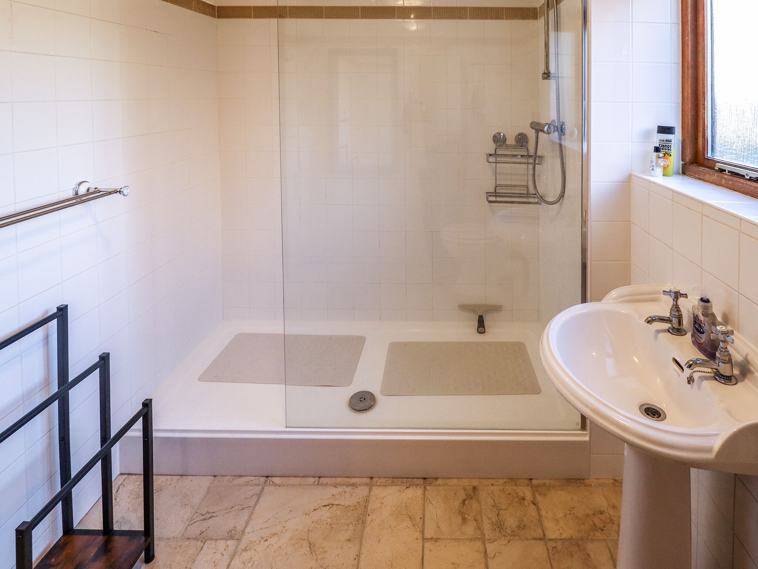 A bathroom with a shower, a sink, and a window.