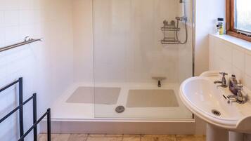 A bathroom with a shower, a sink, and a window.