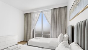 Moderni hotellihuone, jossa on suuri ikkuna, sänky, yöpöytä ja sängynpääty.