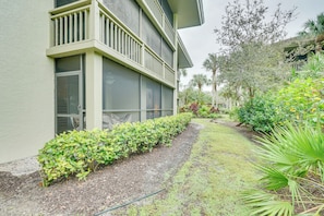 A building with a green facade, large windows, and a well-maintained garden with various plants and a pathway. - Bonita Springs Condo w/ Community Pool! (Bonita Springs)