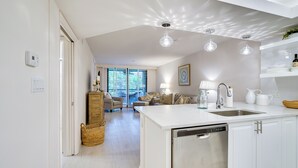 A modern kitchen with white cabinetry, a dishwasher, and a central island with a sink. - Bonita Springs Condo w/ Community Pool! (Bonita Springs)