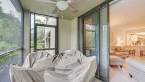 A covered outdoor seating area with a ceiling fan, large windows, and a view of the interior living space. - Bonita Springs Condo w/ Community Pool! (Bonita Springs)