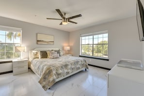 A bedroom with a bed, nightstands, a ceiling fan, a window, and a desk. - Winter Getaway: Destin Condo by Golf & Dining (Destin)