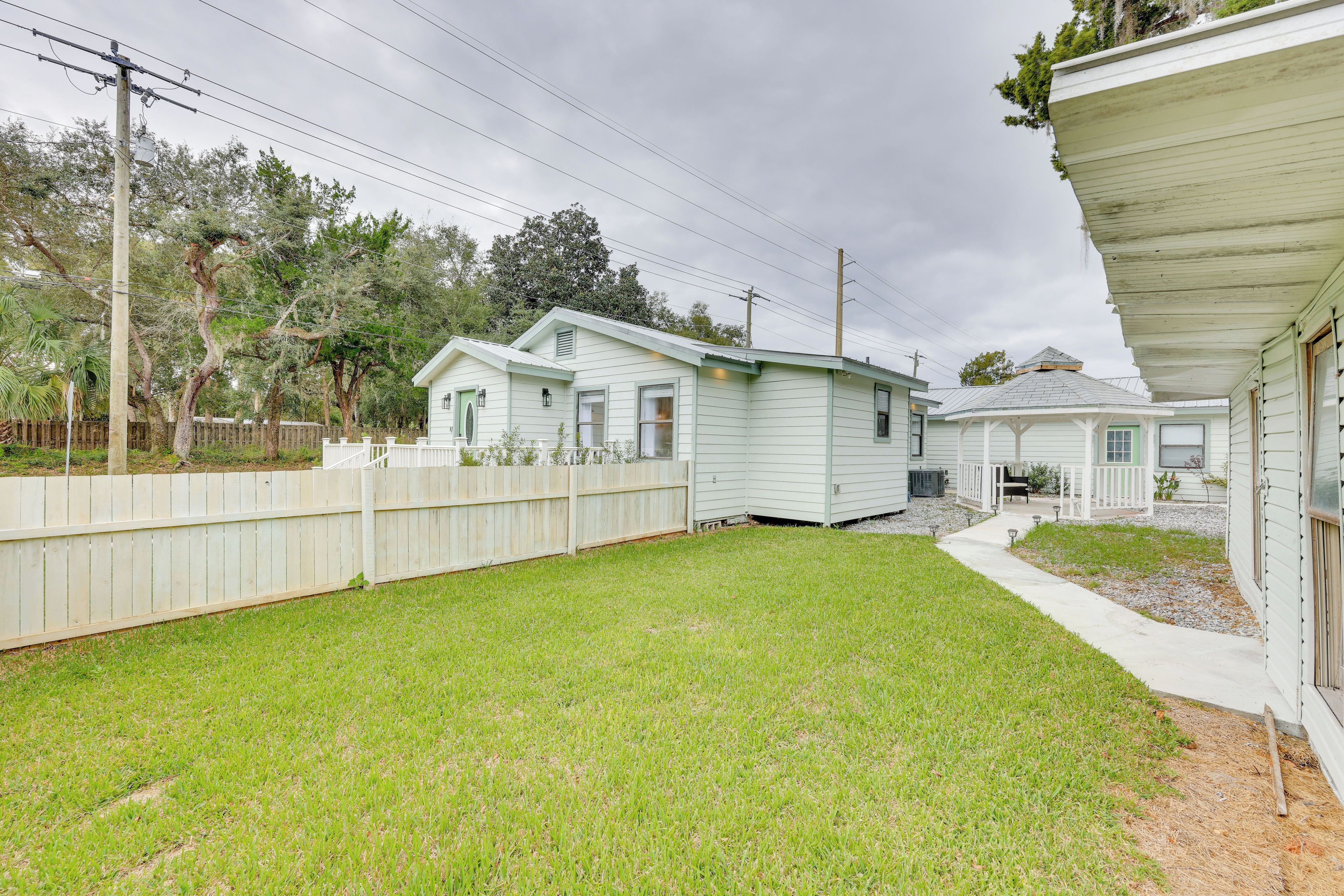 A residential area with two single-story houses, a wooden fence, and a grassy yard.