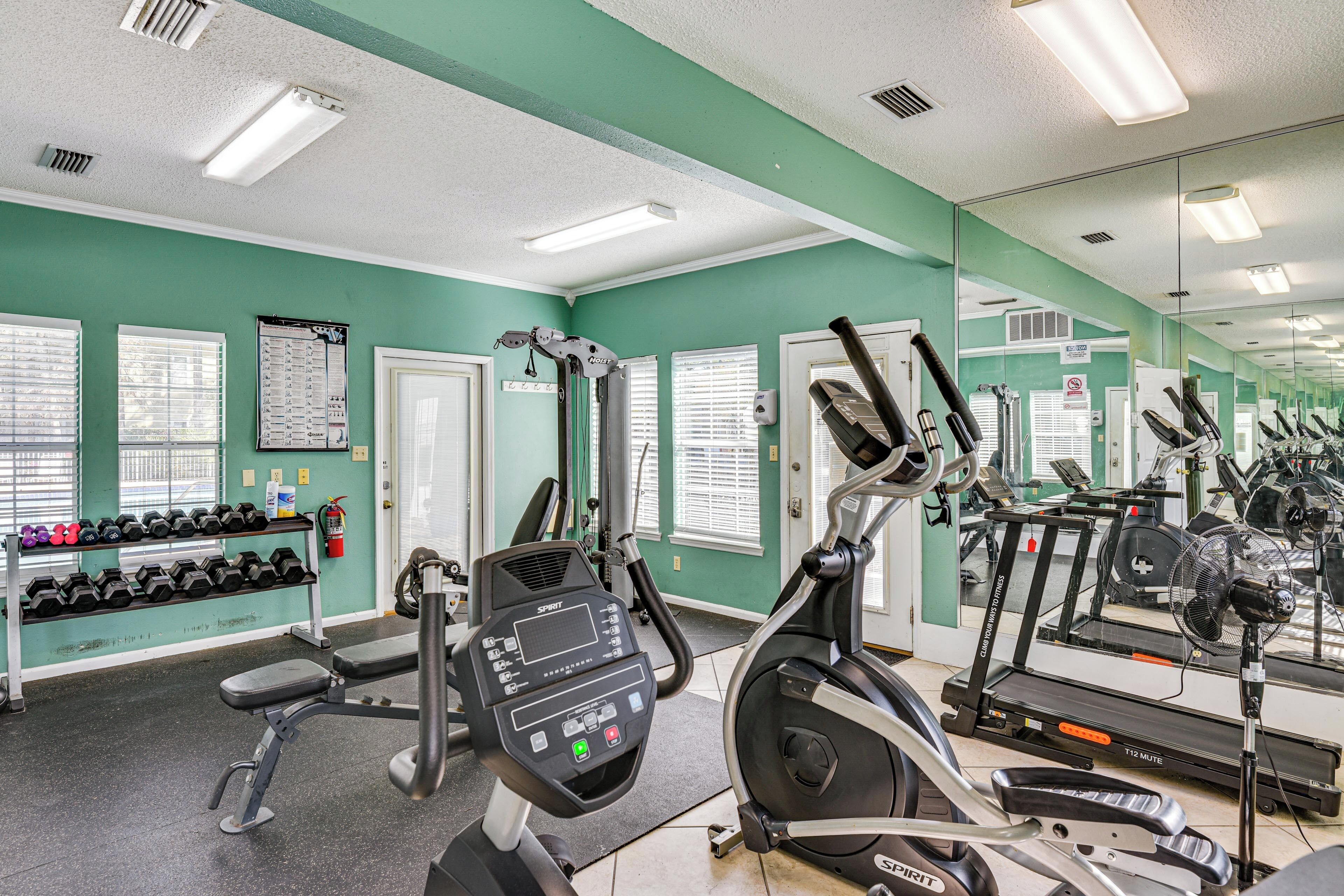 A gym with exercise equipment, a weight rack, and a large mirror.