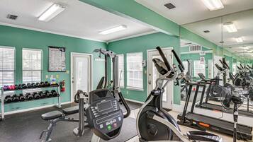 A gym with exercise equipment, a weight rack, and a large mirror.