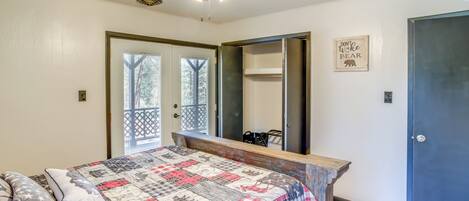 A bedroom with a bed, a ceiling fan, a window, a door, and a mirror.
