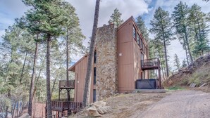 A cabin with a stone exterior, wooden deck, and a view of the surrounding forest. - Ruidoso Cabin Retreat w/ Multi-level Deck (Ruidoso)